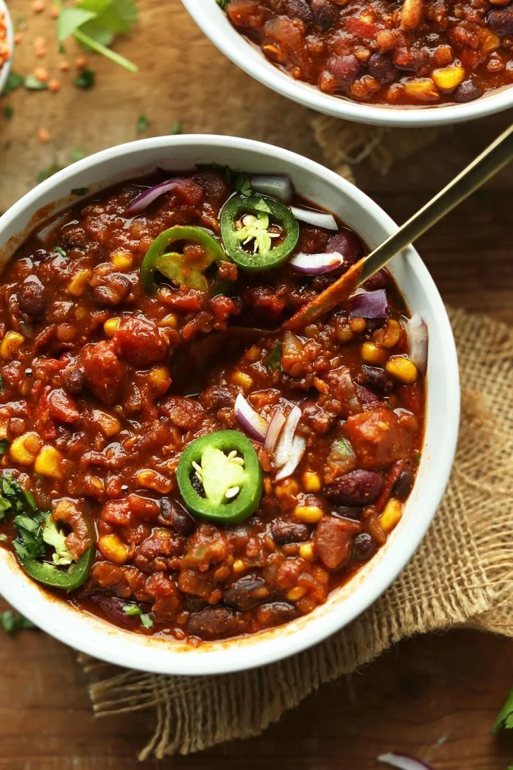 A bowl of hearty vegan chili topped with fresh herbs and spices.