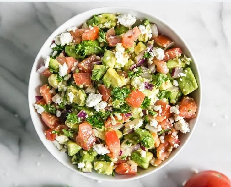 Creamy avocado feta dip served in a bowl with fresh ingredients around it.