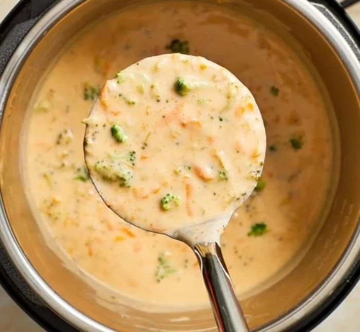 Bowl of creamy Broccoli Cheddar Soup topped with shredded cheddar cheese.