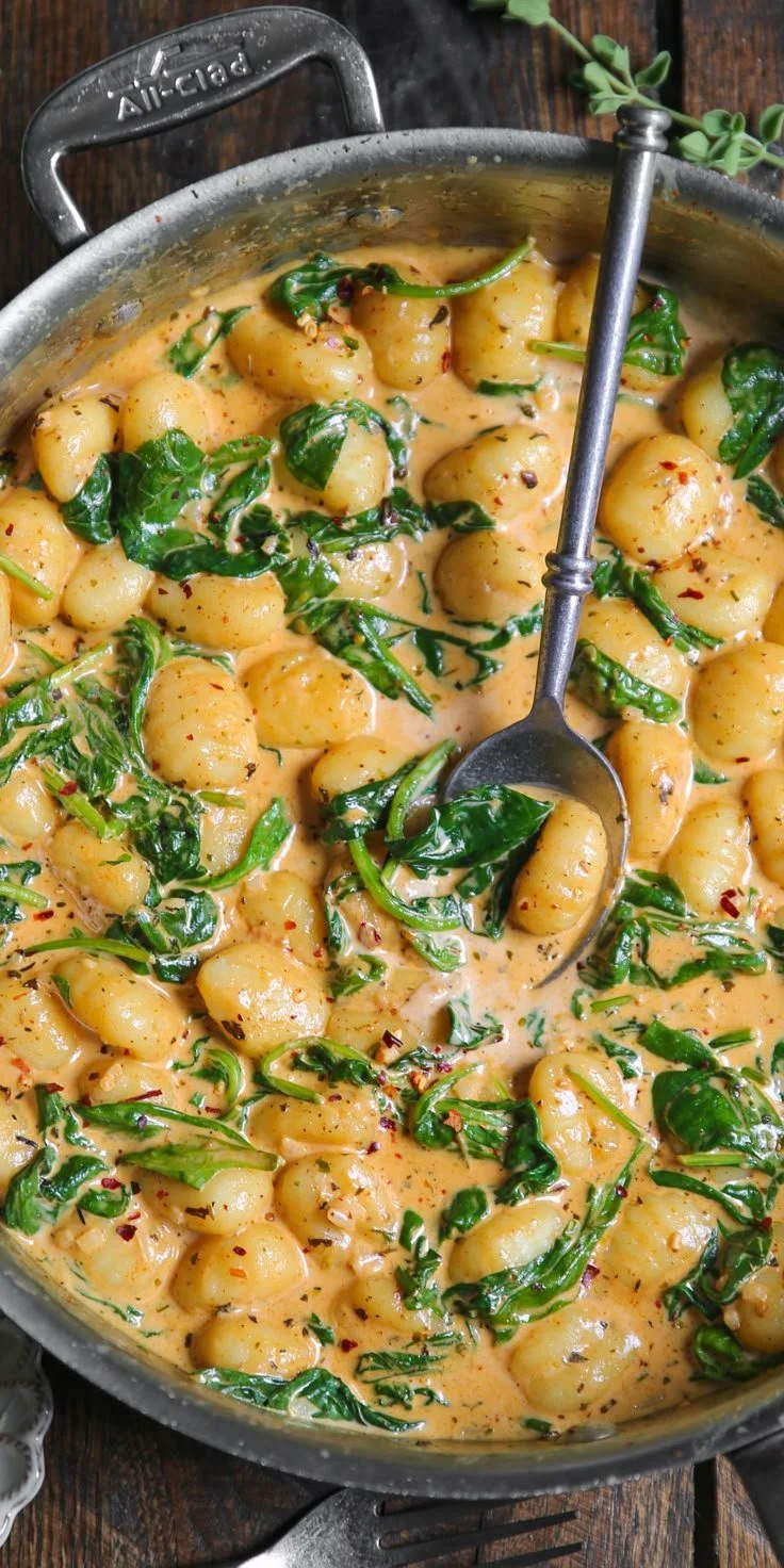 Plate of creamy spinach gnocchi topped with parmesan cheese and herbs