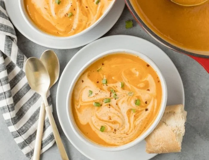 Bowl of easy sweet potato soup topped with cream and herbs