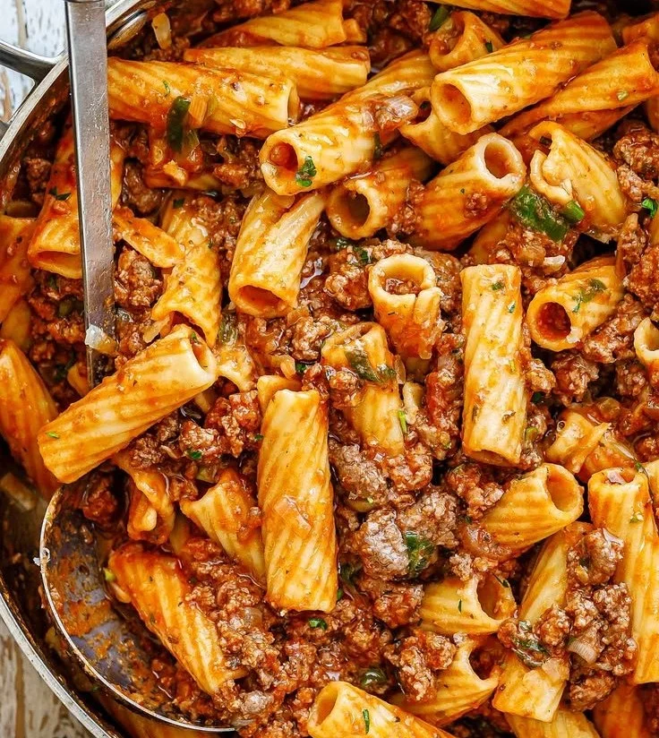 Plate of ground beef pasta served with fresh herbs and cheese on top