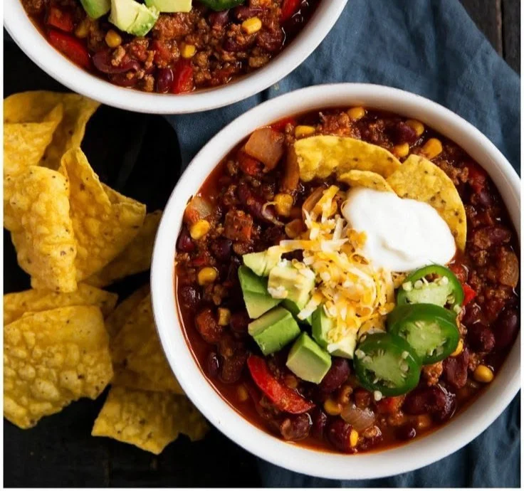 A bowl of colorful, nutritious healthy chili topped with fresh herbs.
