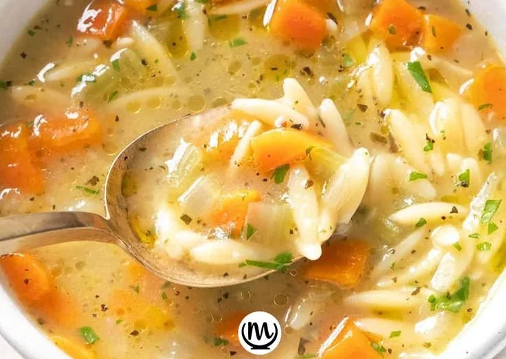 Bowl of delicious orzo soup with vegetables and herbs