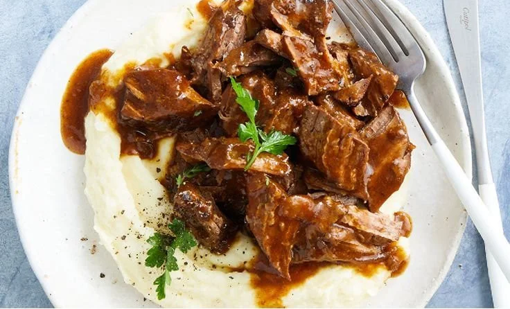 Slow cooker braised steak with onions served on a plate
