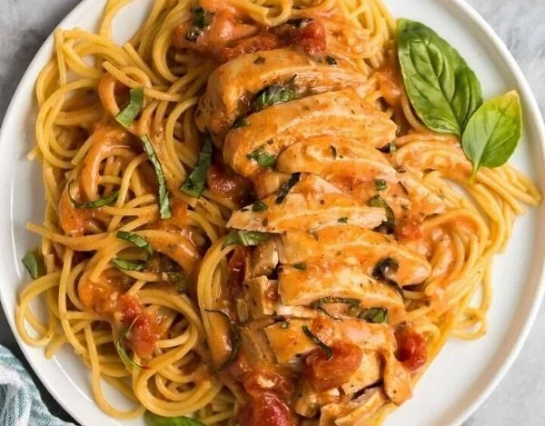 Slow cooker creamy tomato basil chicken served on a plate with fresh basil garnish