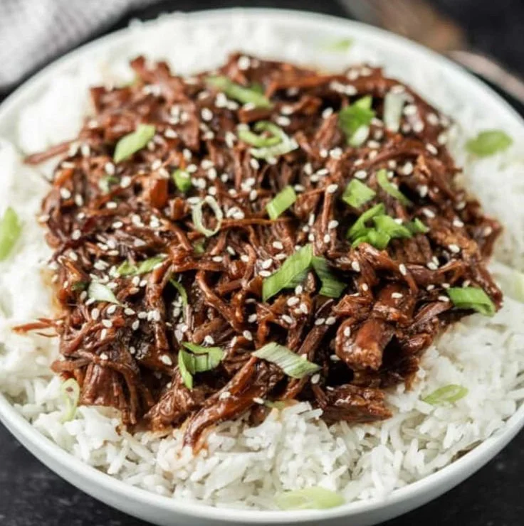 Bowl of Slow Cooker Korean Beef garnished with green onions and sesame seeds