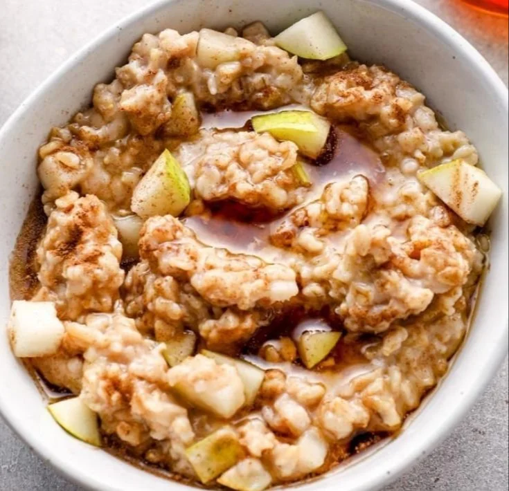 Bowl of spiced pear oatmeal topped with cinnamon and nuts