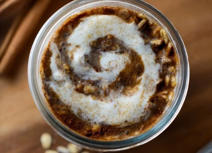 Bowl of creamy cinnamon roll overnight oats topped with cinnamon and nuts