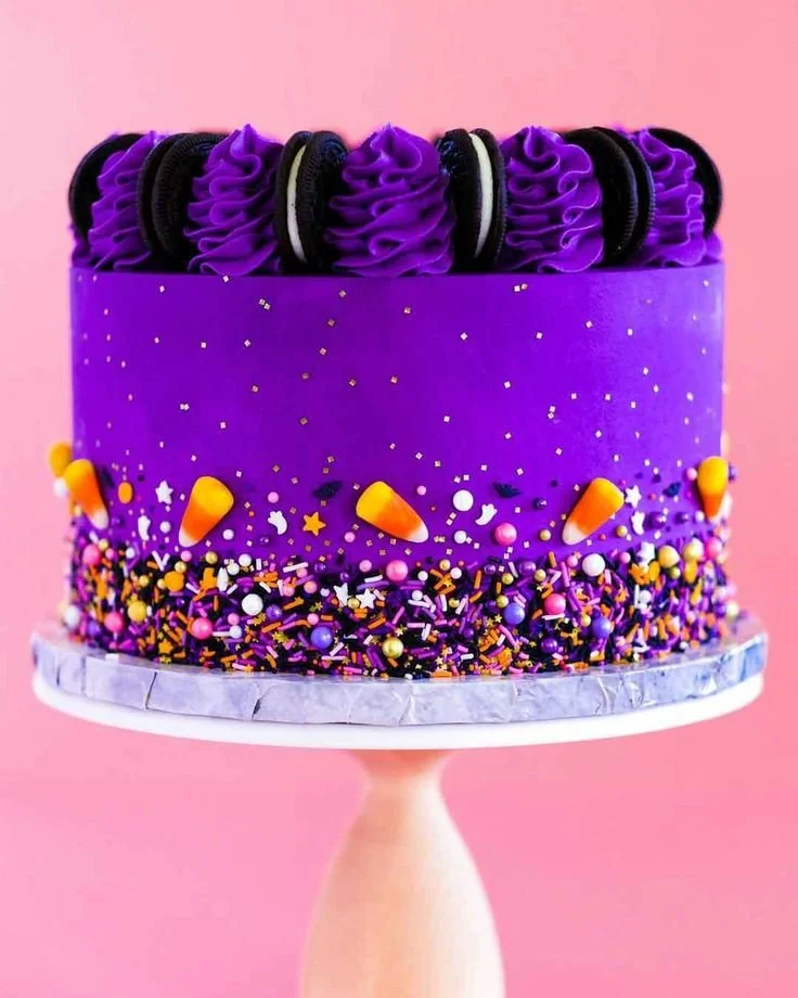 Purple Halloween cake with colorful frosting, sprinkles, and black forks.